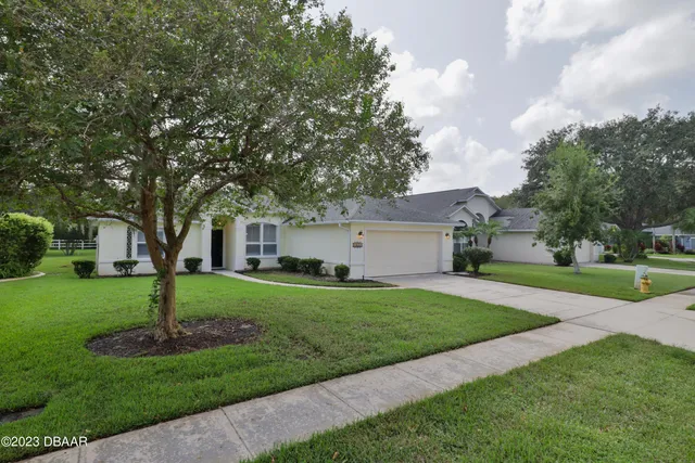 a front view of a house with a garden and trees