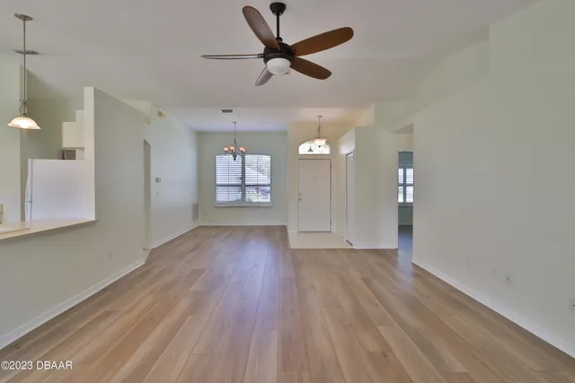 an empty room with wooden floor and a ceiling fan
