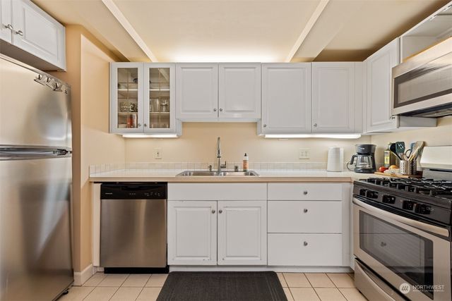 a kitchen with white cabinets a refrigerator and a sink