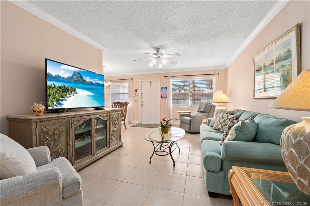 2600 Southeast Ocean Boulevard, Unit EE12 Stuart, FL 34996 - Photo 3 of 43 a living room with furniture a flat screen tv and a floor to ceiling window