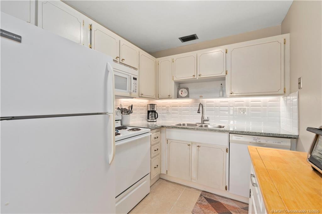 2600 Southeast Ocean Boulevard, Unit EE12 Stuart, FL 34996 - Photo 7 of 43 a kitchen with stainless steel appliances granite countertop a sink a stove a refrigerator and white cabinets