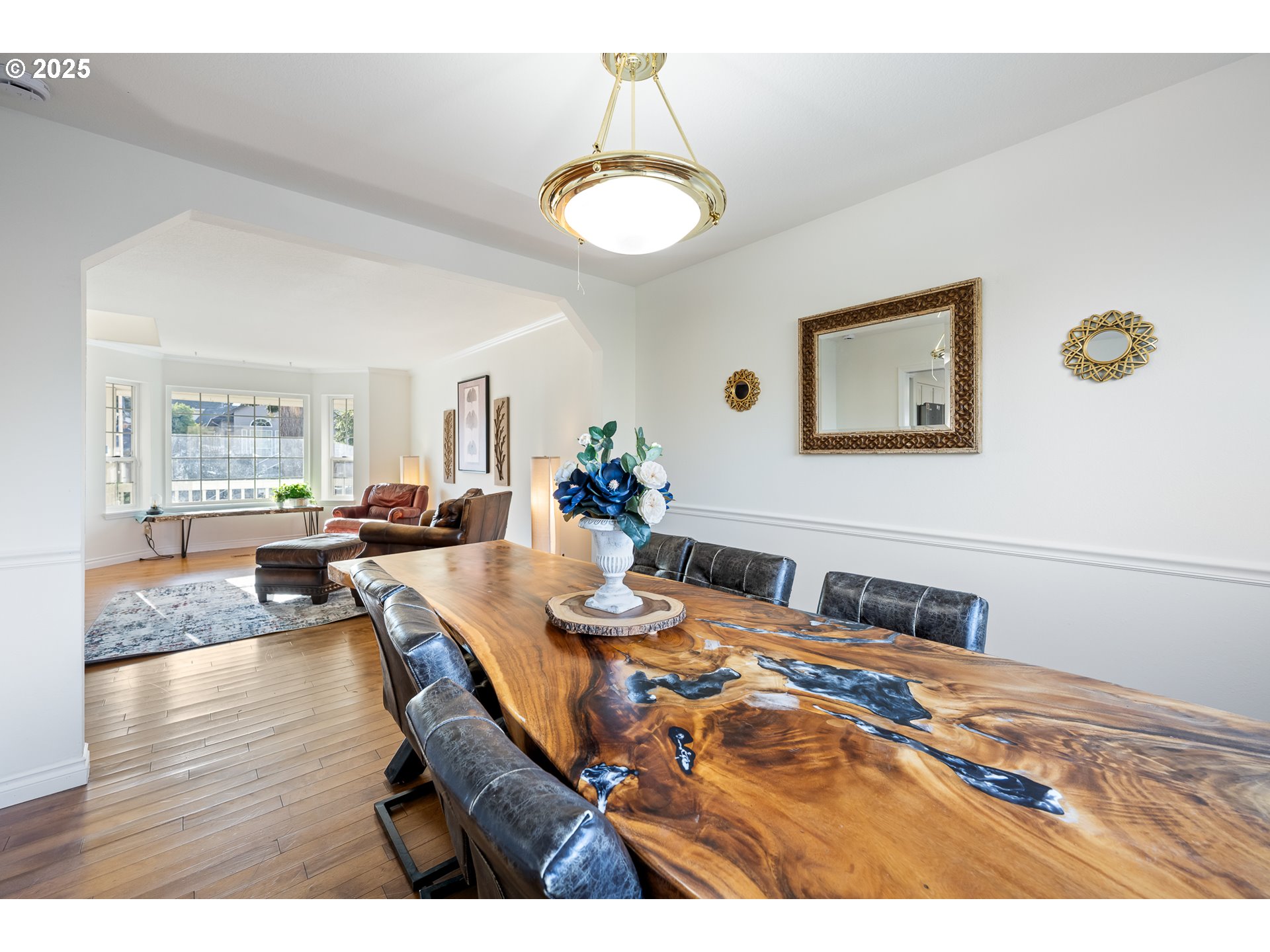 16033 Northwest Ridgetop Lane Beaverton, OR 97006 - Photo 5 of 42 a dining room with wooden floor a chandelier a wooden table and chairs
