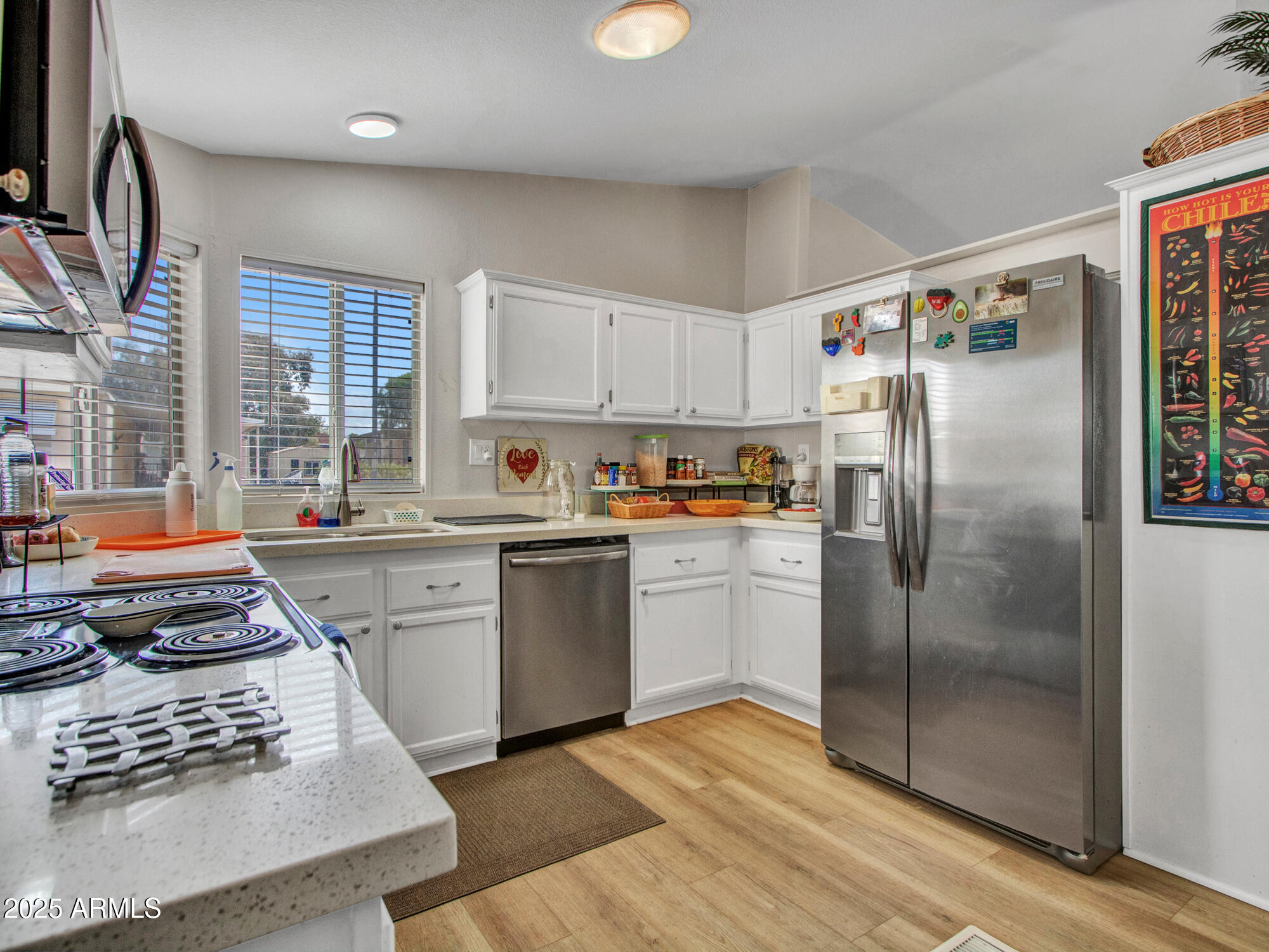 6227 North Litchfield Road, Unit 69 Litchfield Park, AZ 85340 - Photo 13 of 30 a kitchen with stainless steel appliances granite countertop a refrigerator a sink dishwasher a stove and white countertops with wooden floor