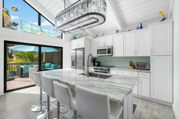 a kitchen with stainless steel appliances granite countertop a stove a refrigerator a kitchen island with white cabinets and wooden floor