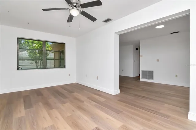 a view of an empty room with window and wooden floor