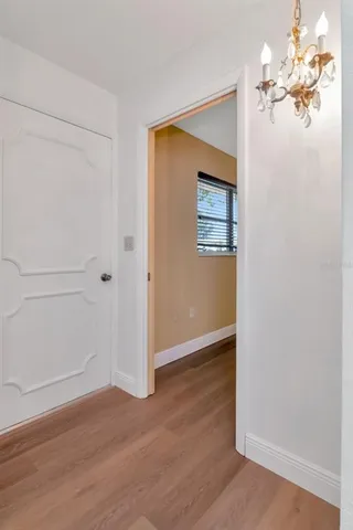 an empty room with wooden floor chandelier fan and windows