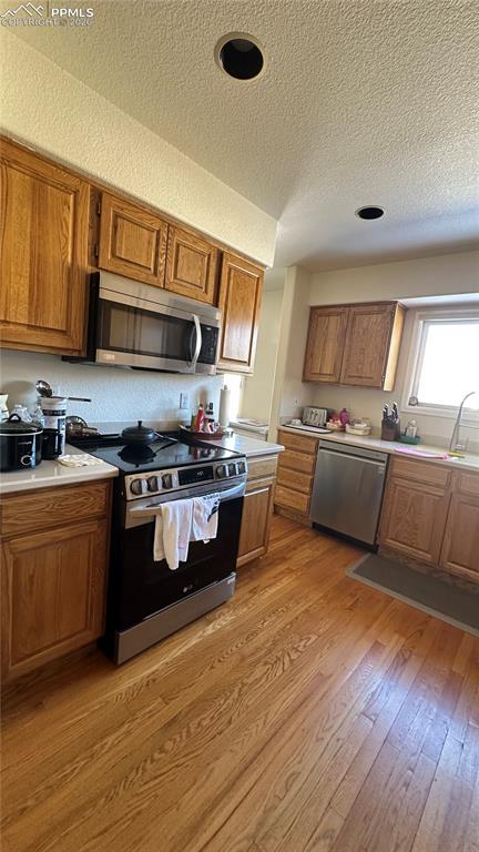 198 Luxury Lane Colorado Springs, CO 80921 - Photo 27 of 34 a kitchen with stainless steel appliances granite countertop a stove a sink dishwasher and a microwave oven with wooden floor