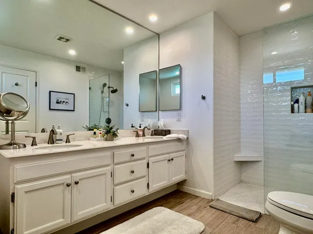 a bathroom with double vanity sink a mirror and a toilet