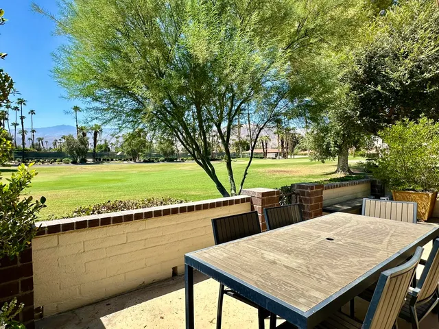 a view of a patio with table and chairs a fire pit and large trees