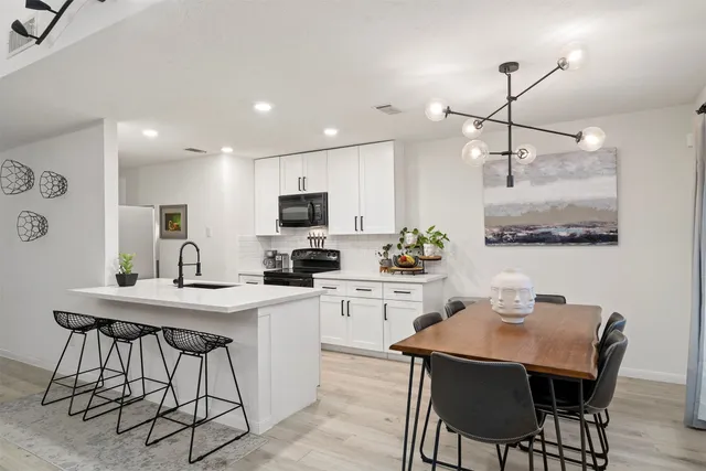 a kitchen with stainless steel appliances kitchen island granite countertop a dining table chairs and white cabinets