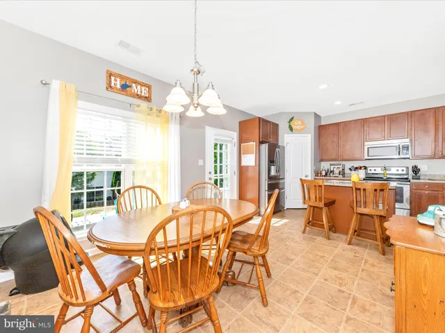 a view of a dining room with furniture a chandelier and kitchen view