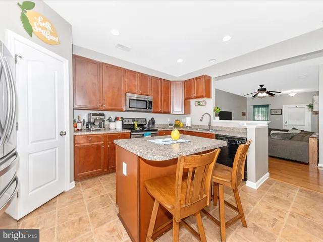 a kitchen with stainless steel appliances kitchen island granite countertop a refrigerator a stove a sink dishwasher and a dining table with wooden floor