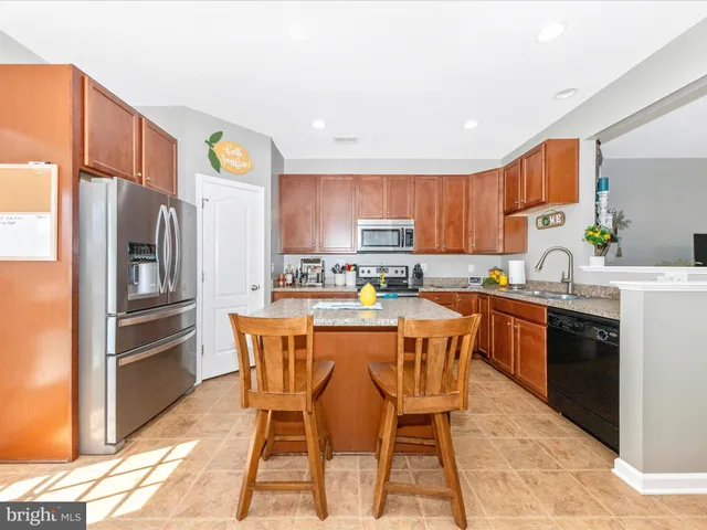 a kitchen with stainless steel appliances granite countertop a refrigerator a stove top oven a sink and dishwasher