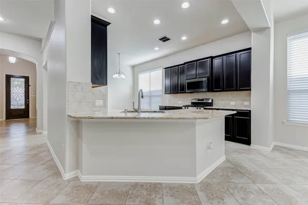 a large kitchen with kitchen island granite countertop a large counter top a sink stainless steel appliances and cabinets