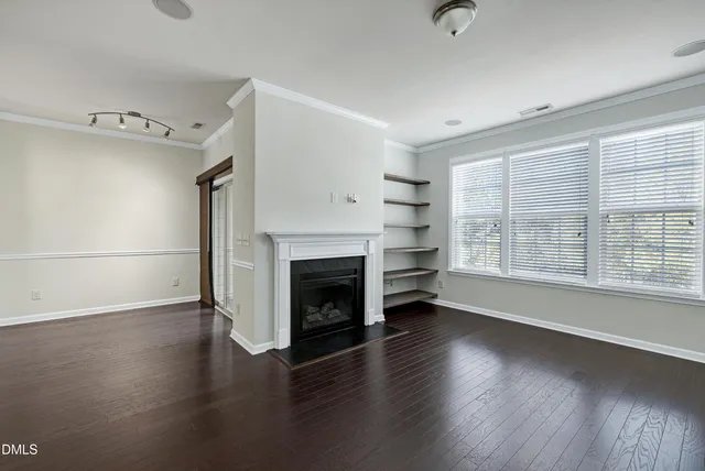 an empty room with wooden floor cabinet and windows