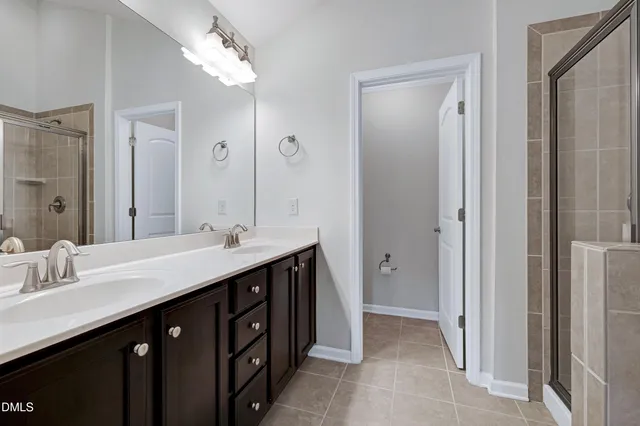 a spacious bathroom with a double vanity sink a mirror and a shower
