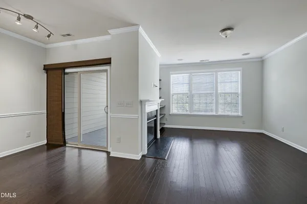 an empty room with wooden floor cabinet and windows