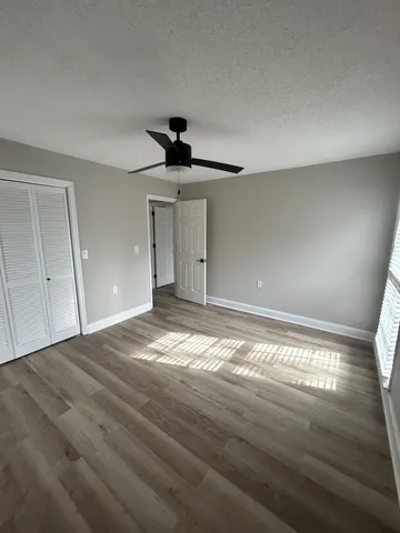 a view of empty room with wooden floor and fan
