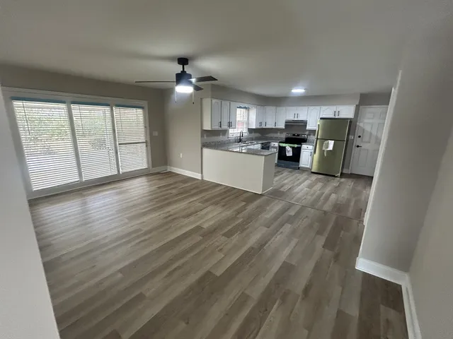a view of large kitchen with wooden floor and stainless steel appliances