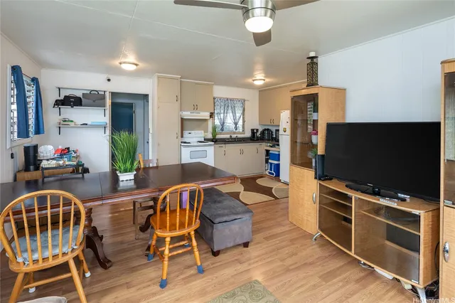 a kitchen with stainless steel appliances granite countertop a stove top oven a sink dishwasher a dining table and chairs with wooden floor