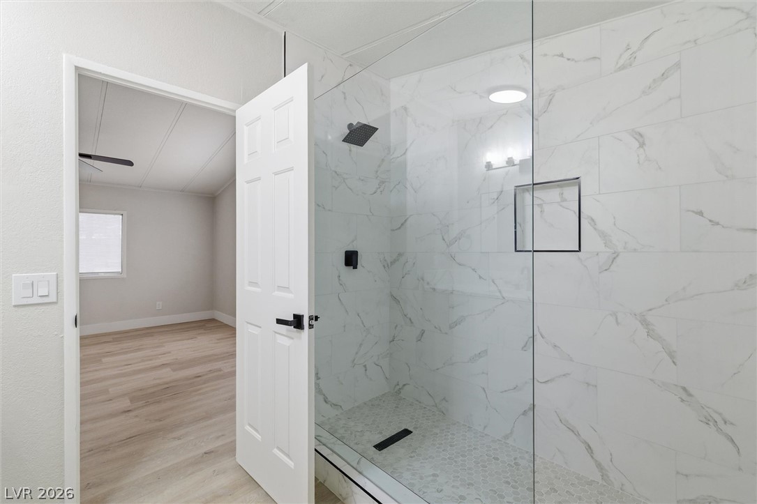 3940 Point Drive Pahrump, NV 89060 - Photo 24 of 35 A sleek, glass-enclosed shower boasts elegant marble-patterned tile, enhancing the modern bathroom design.