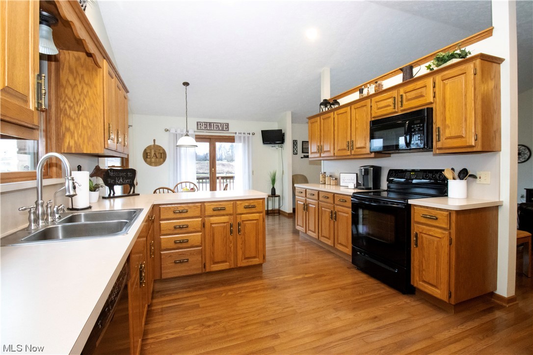 8084 Millbrook Road Shreve, OH 44676 - Photo 7 of 35 Kitchen featuring sink, pendant lighting, light hardwood / wood-style floors, kitchen peninsula, and black appliances