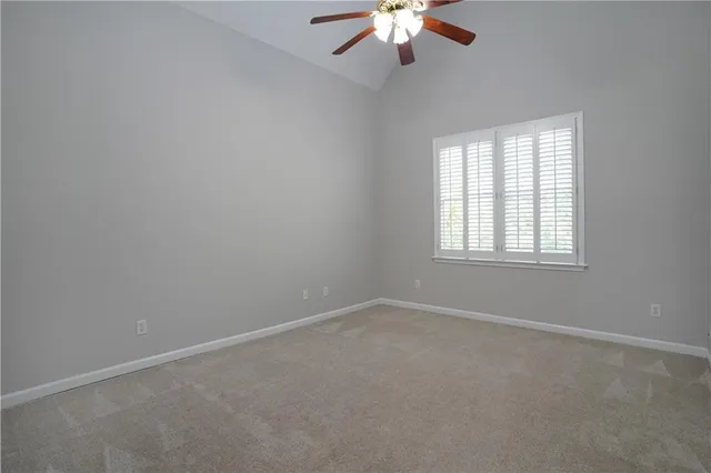 a view of an empty room with chandelier fan and kitchen view