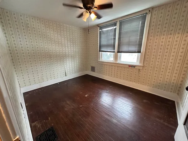 an empty room with wooden floor fan and windows