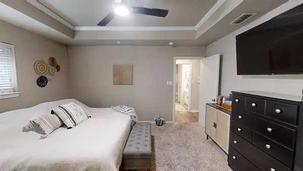 a bedroom with a bed and a flat tv screen on a dresser