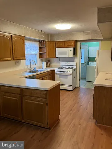 a kitchen with stainless steel appliances granite countertop a sink a stove a refrigerator cabinets and wooden floor