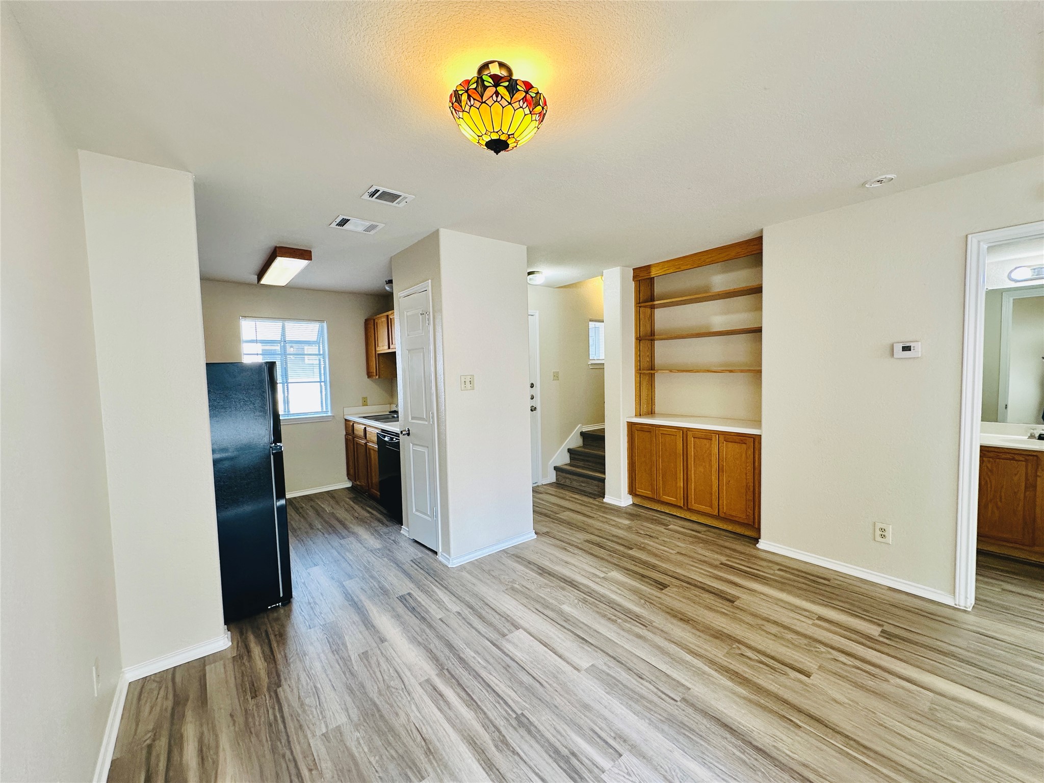 8814 Schick Road, Unit C Austin, TX 78729 - Photo 5 of 35 Functional kitchen and living area with wood-look flooring and built-in shelving.
