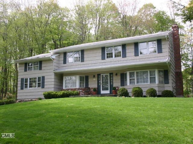 a front view of a house with garden and trees