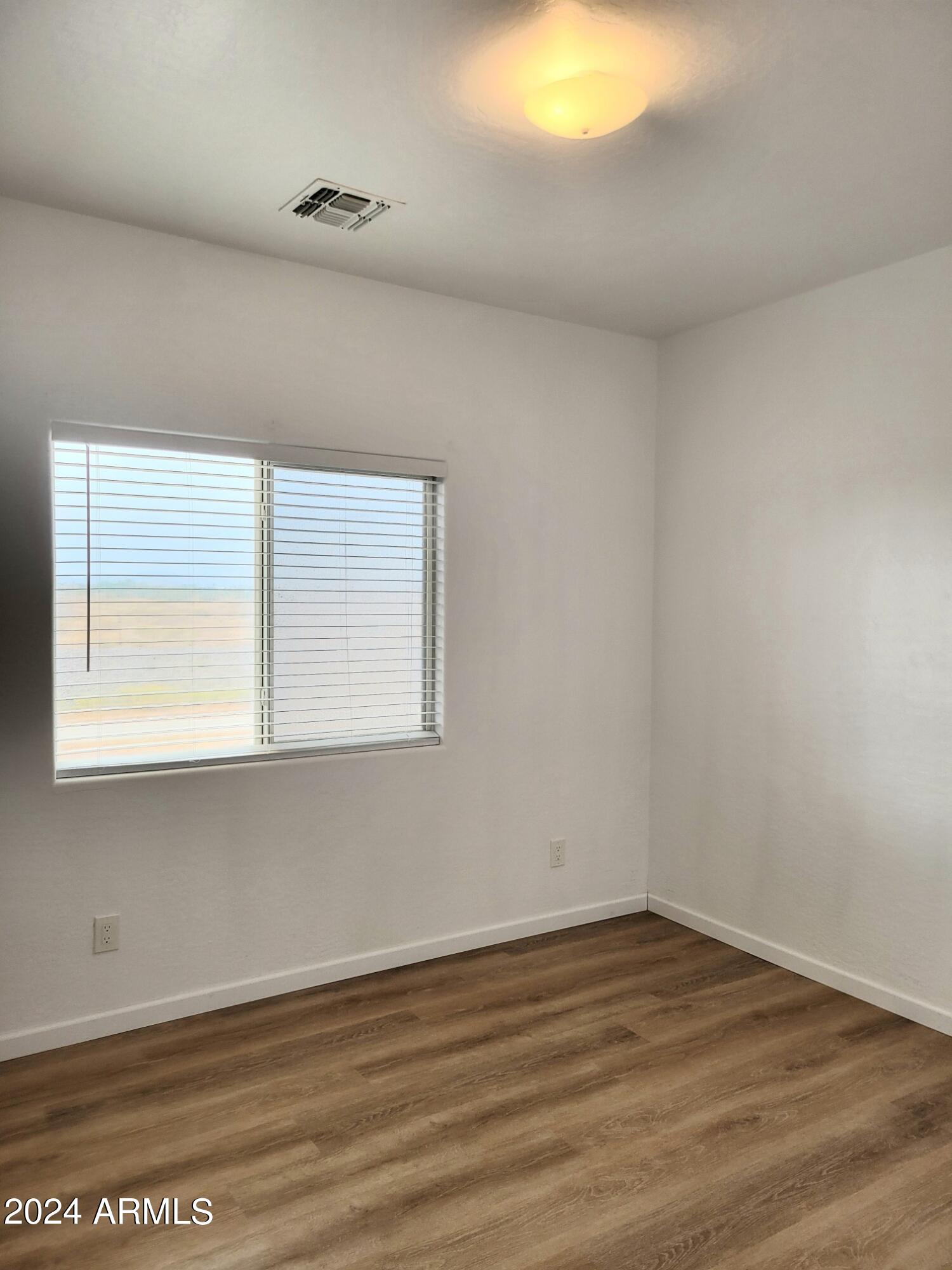 2300 East Magma Road, Unit 170 San Tan Valley, AZ 85143 - Photo 11 of 22 a view of an empty room with wooden floor and a window