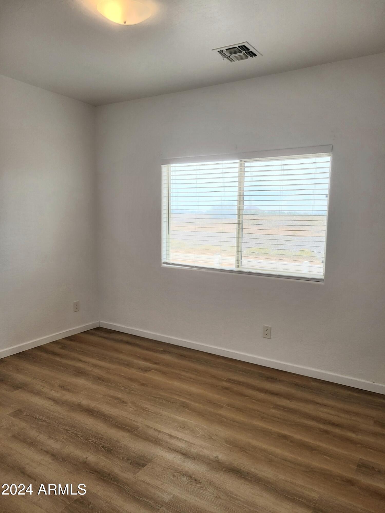 2300 East Magma Road, Unit 170 San Tan Valley, AZ 85143 - Photo 13 of 22 an empty room with wooden floor and windows