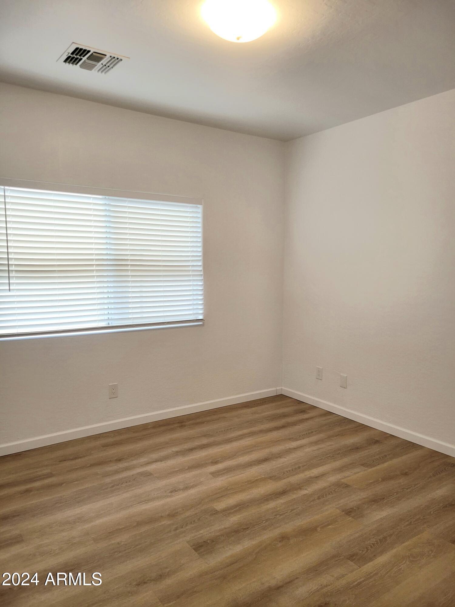 2300 East Magma Road, Unit 170 San Tan Valley, AZ 85143 - Photo 15 of 22 a view of an empty room with wooden floor and a window