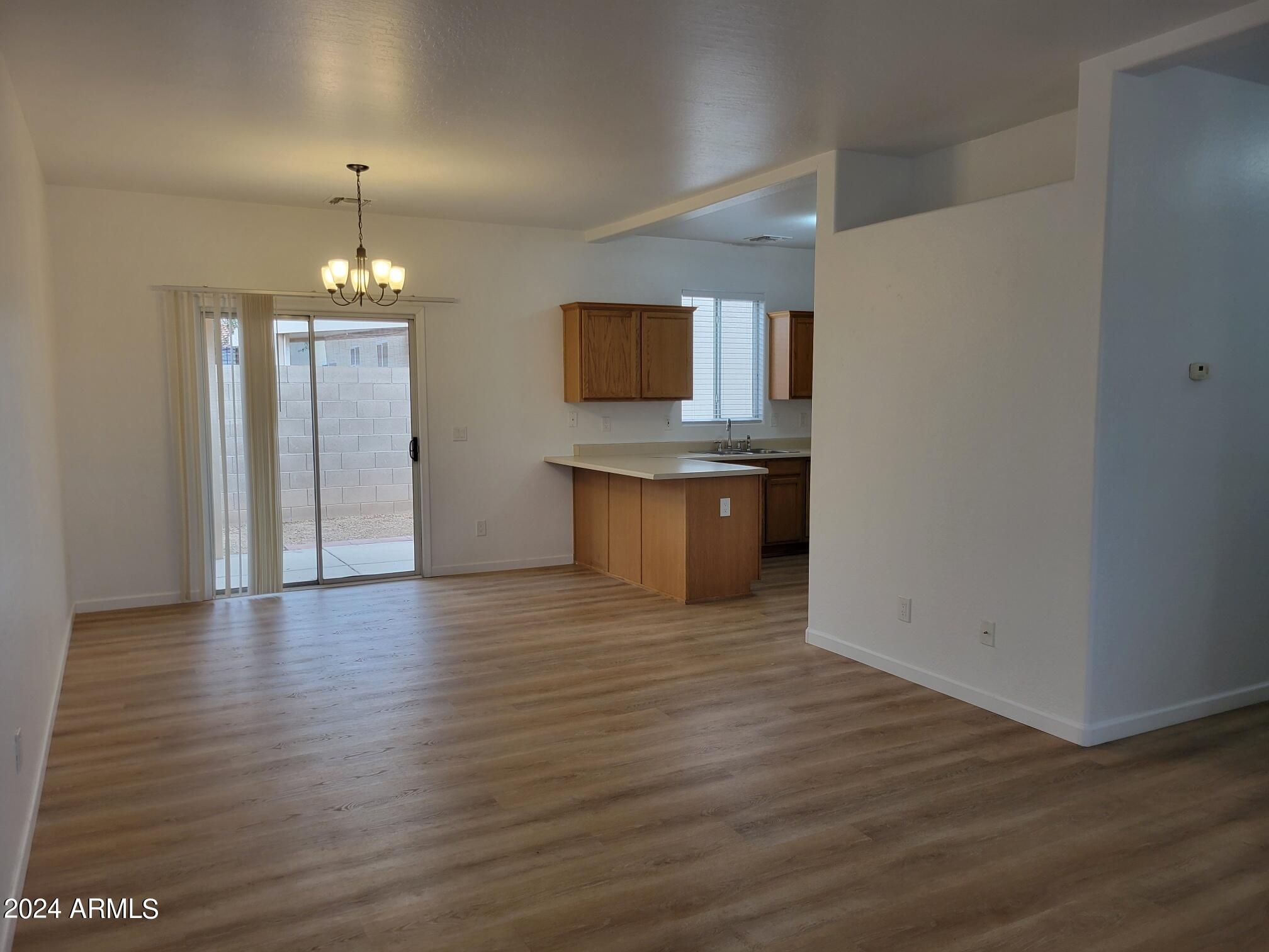 2300 East Magma Road, Unit 170 San Tan Valley, AZ 85143 - Photo 6 of 22 an empty room with wooden floor kitchen and chandelier