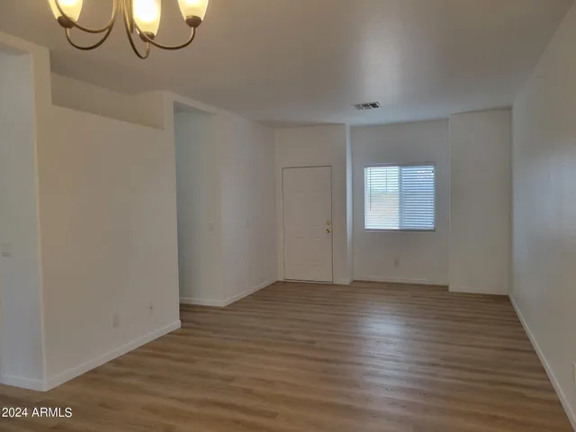 a view of an empty room with wooden floor and windows