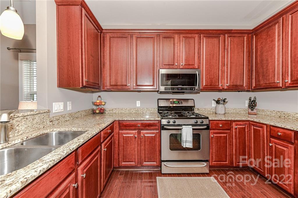 78078 Rillstone Drive Lancaster, SC 29720 - Photo 11 of 42 a kitchen with stainless steel appliances granite countertop a stove a sink dishwasher and a microwave oven with wooden cabinets