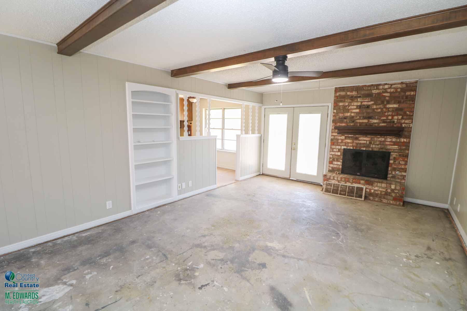 705 West Virginia Street Floydada, TX 79235 - Photo 3 of 15 a view of an empty room with a fireplace and a window
