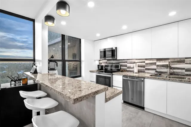 a kitchen with stainless steel appliances kitchen island granite countertop a stove refrigerator and microwave