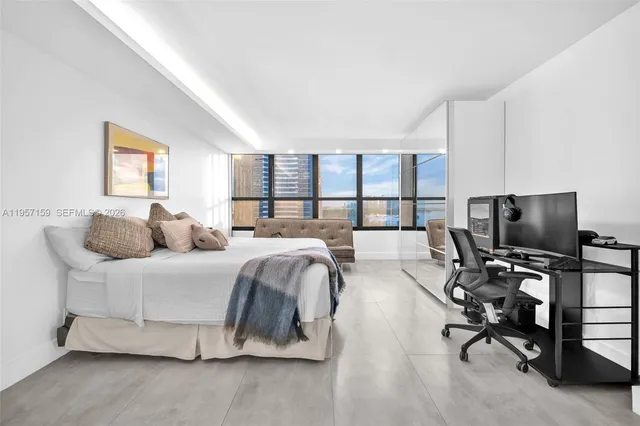 a bed room with a bed television and a large window