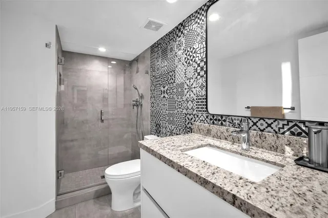 a bathroom with a granite countertop sink a toilet and shower