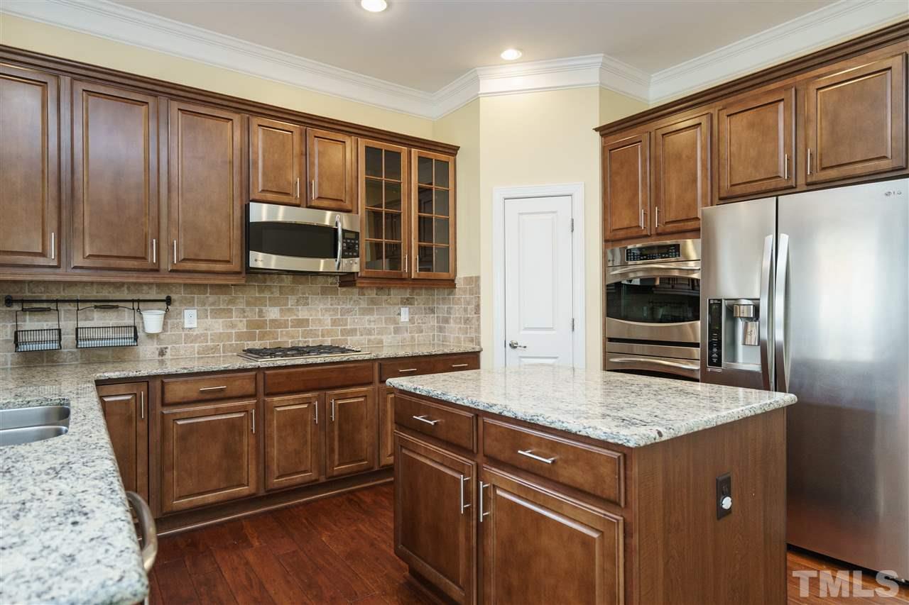 1334 Rodessa Run Raleigh, NC 27607 - Photo 9 of 25 a kitchen with kitchen island granite countertop wooden cabinets stainless steel appliances and a sink