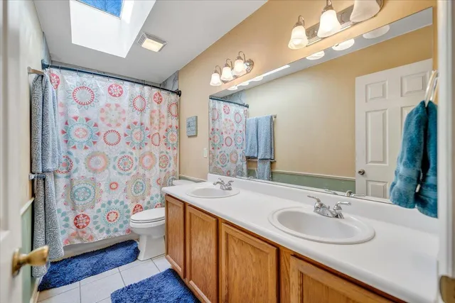 a bathroom with double vanity sink a mirror a lamp and bathtub
