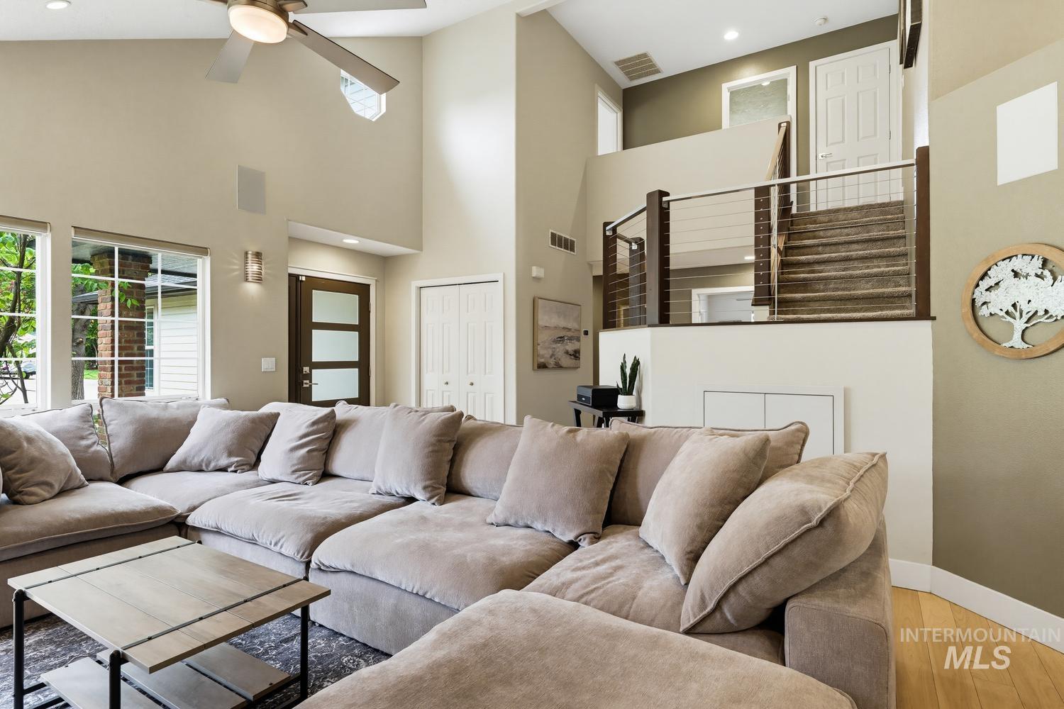 369 South Winthrop Way Boise, ID 83709 - Photo 6 of 50 Two-story living area with vaulted ceilings, large windows, wood-finish flooring, and a modern cable railing staircase
