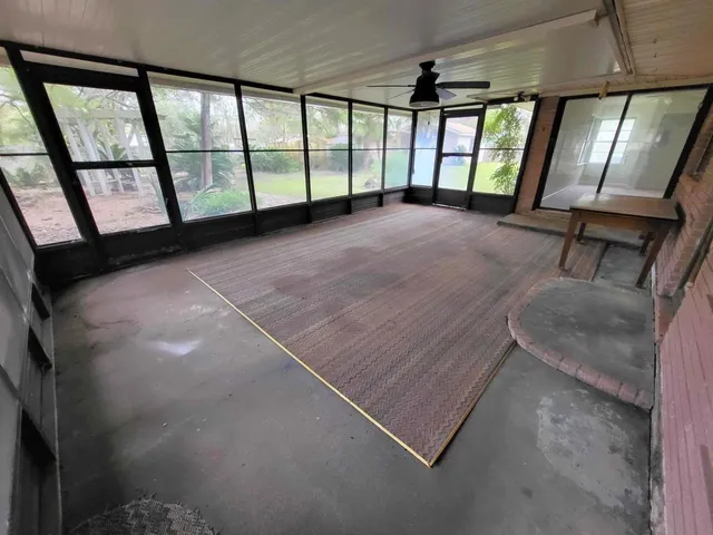 an empty room with wooden floor windows and fireplace