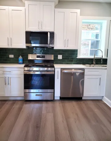 a kitchen with stainless steel appliances granite countertop a stove a sink and a microwave