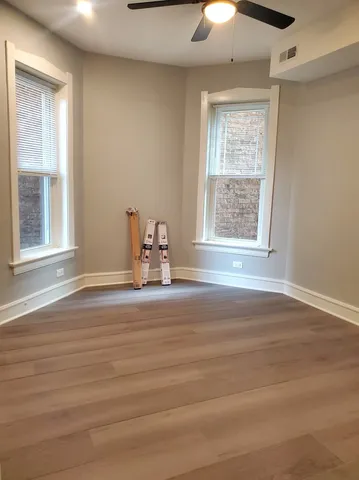 a view of empty room with wooden floor and fan