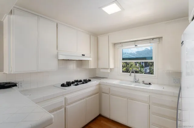a kitchen with white cabinets and sink