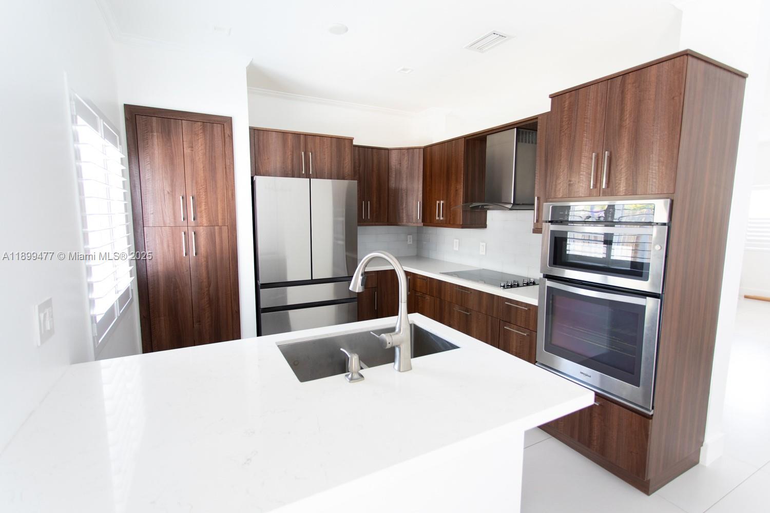 14219 Southwest 126th Place Miami, FL 33186 - Photo 9 of 26 a kitchen with stainless steel appliances kitchen island a refrigerator sink and cabinets